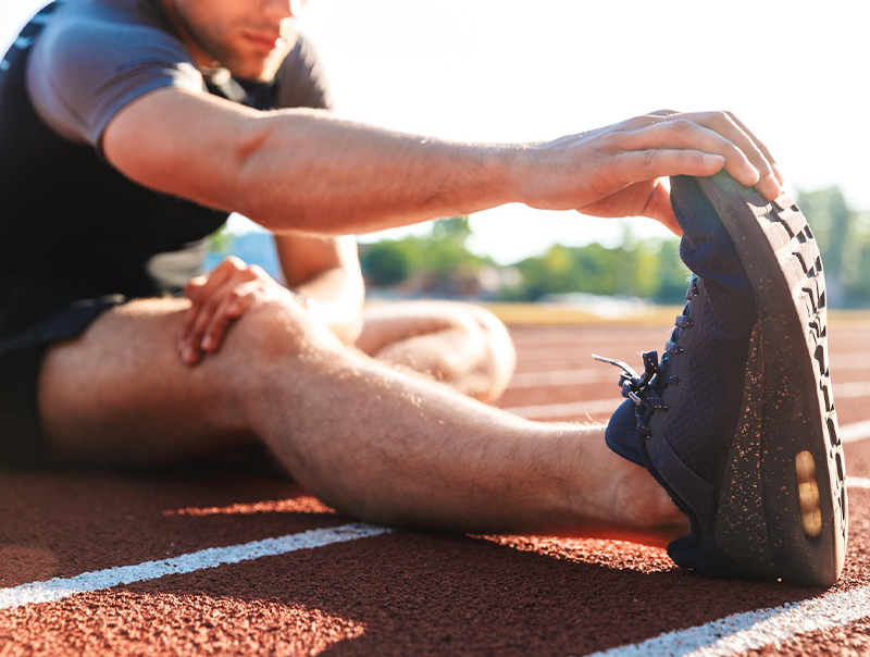 young healthy athlete stretching on a track