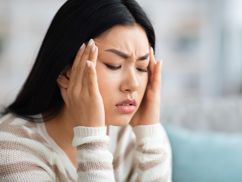 Young asian woman suffering from migraine at home